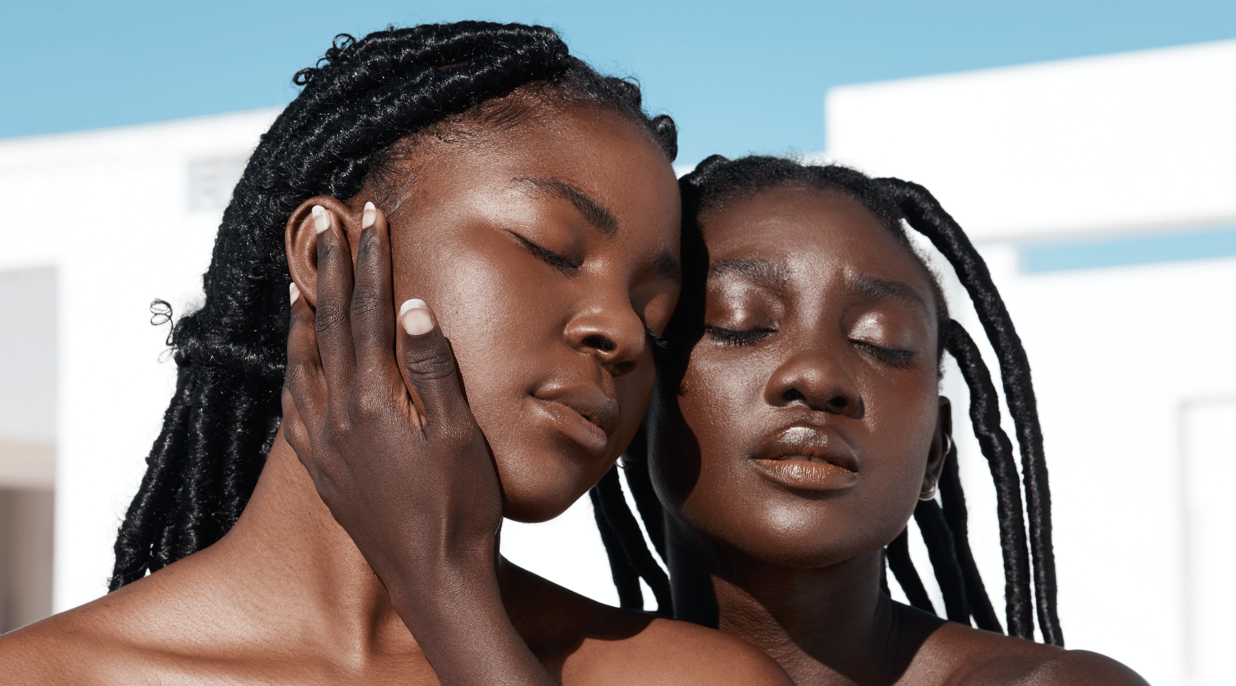 Cropped shot of two women with brown skin in the sun embracing