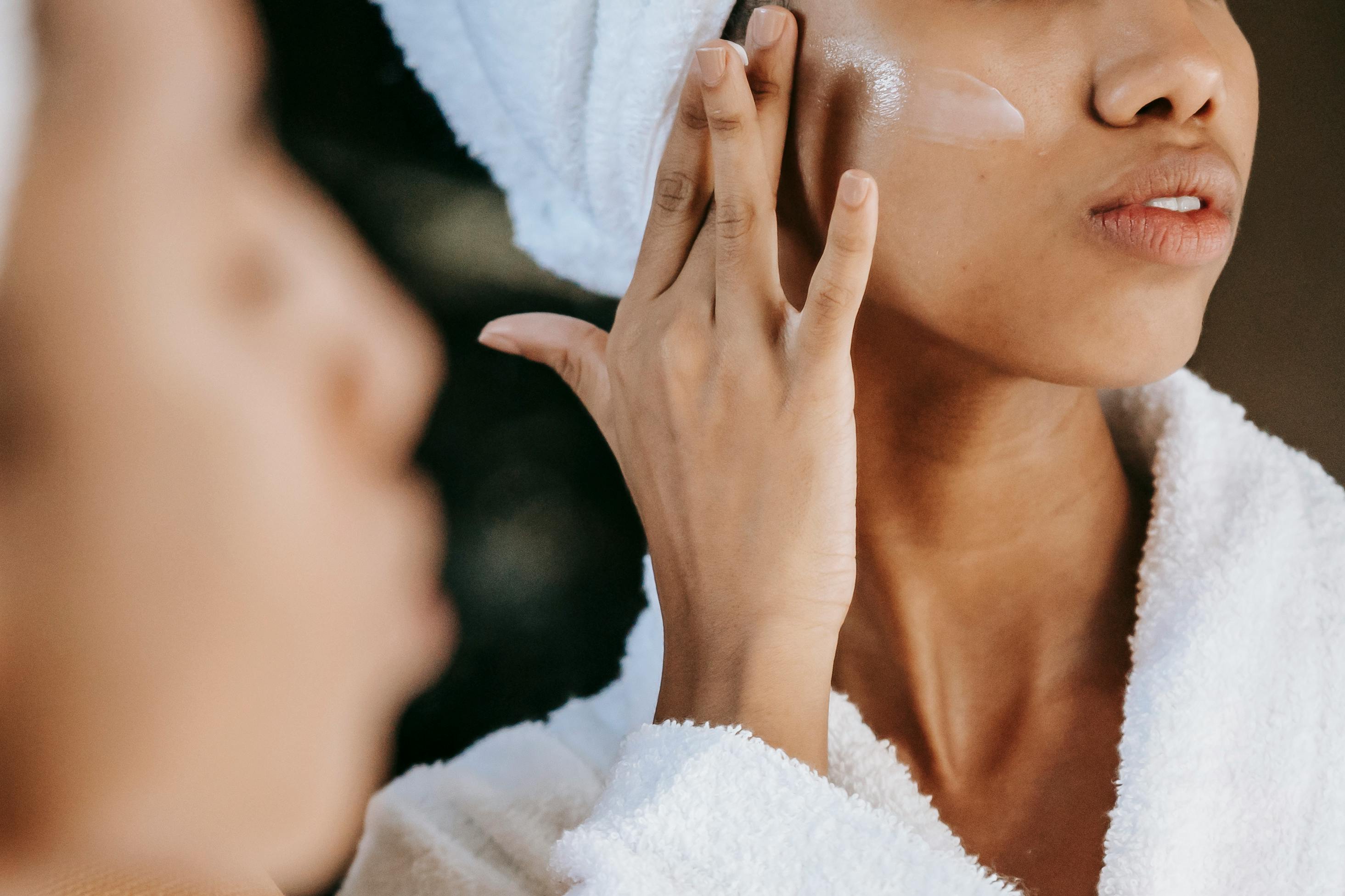 women adding product to her check bone while looking into the mirror